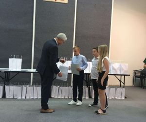 Uczeń odbiera upominek od senatora