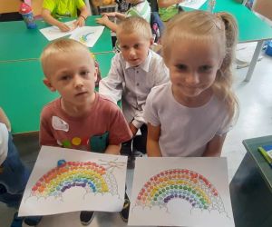 Chłopiec i dziewczynka trzymają w dłoniach prace wyklejone kuleczkami z plasteliny