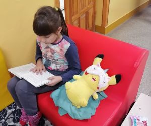 Uczennica siedzi na pufie i czyta książkę