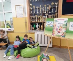 Uczniowie leżą na pufie i czytają książki