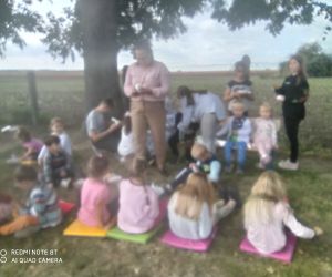 dzieci siedzą na trawce i spożywają pieczone ziemniaki