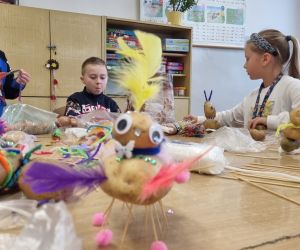 Dzieci pracują przy stolikach tworząc ozdoby do swoich ludków