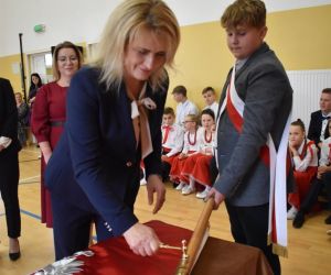 Pani Sekretarz Gminy Hrubieszów przybija gwóźdź pamiątkowy do drzewca sztandaru szkoły