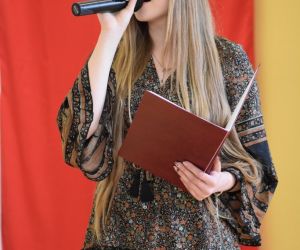 Dawna uczennica szkoły śpiewa przy mikrofonie