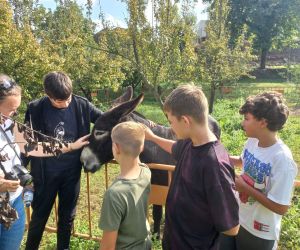 Nauczycielka z Polski z uczniami polskimi i portugalskimi głaszczą osiołka