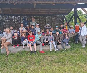 Grupa dzieci z nauczycielkami przy drewnianej łodzi gockiej