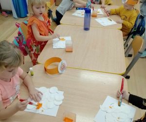Dzieci wykonują pracę plastyczną „Dynia z miękkich płatków”.