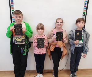 Uczniowie trzymają wykonane przez siebie prace plastyczne