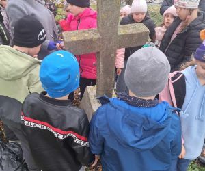 Nauczycielka rozmawia z uczniami na temat mogiły