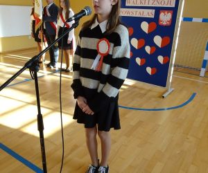 Uczennica w stroju galowym recytuje przy mikrofonie