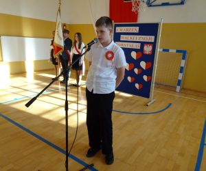 Uczeń w stroju galowym recytuje przy mikrofonie