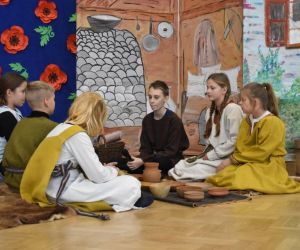 Uczniowie w strojach Piastów siedzą przy ognisku