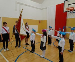 Pierwszoklasiści składają ślubowanie na sztandar szkoły; obok stoi poczet sztandarowy