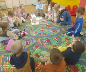 Dzieci siedzą na dywanie z misiami.