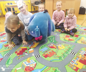 Dzieci siedzą z dużym pluszowym misiem.