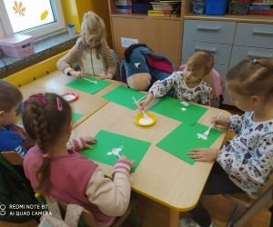 Dzieci malują polarne misie na zielonym kartonie.