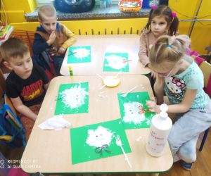 Dzieci malują polarne misie na zielonym kartonie.