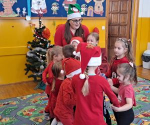 Dzieci tańczą wraz z nauczycielką w kole trzymając się za ręce.