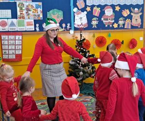 Dzieci tańczą wraz z nauczycielką w kole trzymając się za ręce.