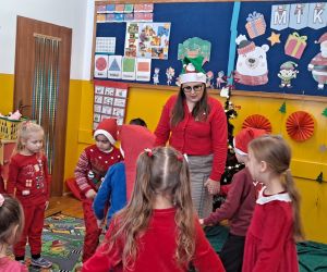 Dzieci tańczą wraz z nauczycielką w kole trzymając się za ręce.