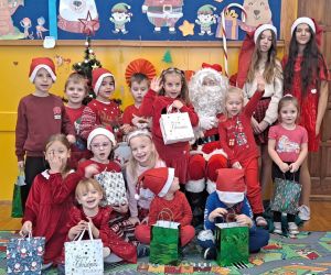 Dzieci prezentują się z Mikołajem i jego pomocnicami.