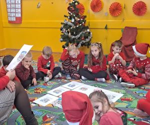 Dzieci słuchają opowiadania czytanego przez nauczycielkę.