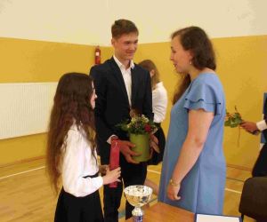 Uczennica i uczeń wręczają kwiaty wychowawczyni klasy VIII