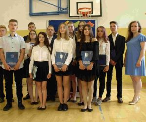 Chłopcy i dziewczęta w strojach galowych - absolwenci szkoły podstawowej z wychowawczynią