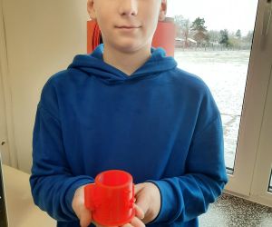 Uczeń trzyma wydrukowany kubek 3D