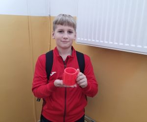 Uczeń trzyma kolejny kubek wydrukowany za pomocą drukarki 3D