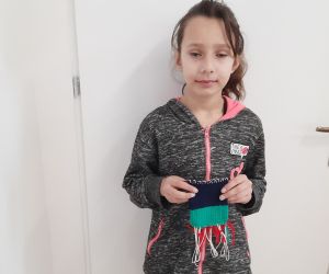 Uczennica trzyma wykonaną na krośnie makatkę