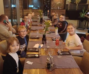 Grupa dzieci siedząca przy wspólnym stole czkająca na posiłek