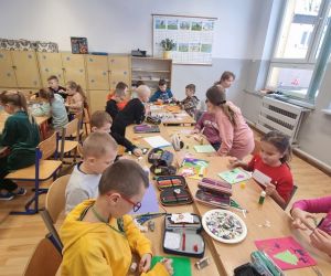  Uczniowie przy stolikach wykonują kartki świąteczne 