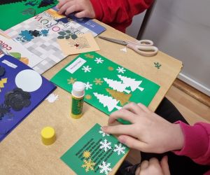 Uczniowie przyklejają ozdoby na kartki