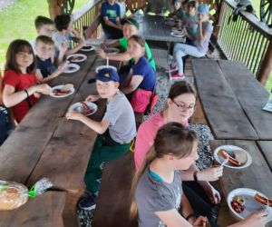 Dziewczęta i chłopcy przy stołach spożywają poczęstunek