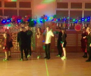 Uczniowie i nauczyciele tańczą belgijkę w sali gimnastycznej