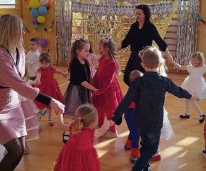 Dzieci z klas młodszych tańczą w kole z nauczycielkami i mamami