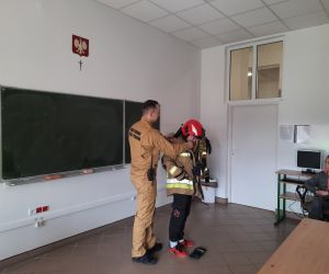 Strażak pomaga uczniowi założyć kurtkę