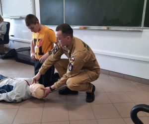 Strażak pokazuje na fantomie jak rozpocząć udzielanie pierwszej pomocy