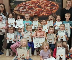Dzieci pozują do zdjęcia z dyplomami z okazji Dnia Pizzy.