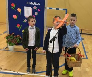 Trzech chłopców stoi przed mikrofonem, jeden trzyma w ręku samolot