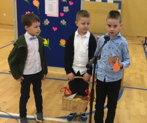 Trzech chłopców stoi przed mikrofonem, jeden trzyma w ręku serduszka