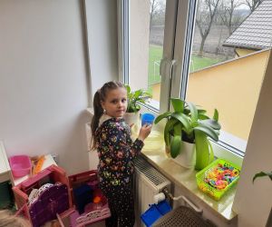 Dziewczynka podlewa roślinę doniczkową