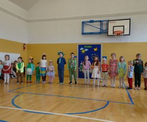 Najmłodsze dzieci w strojach wiosennych stoją na tle dekoracji wiosennej