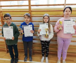 Czworo uczniów klasy trzeciej z dyplomami i pucharami