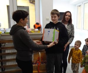 Mama z Rady Rodziców wręcza nagrodę uczniowi klasy piątej