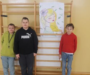 Uczniowie klasy piątej na tle swojej pracy Pani Wiosna