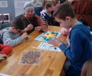 Uczniowie klasy trzeciej wykonują paciorki pod opieką prowadzącej w stroju gockim