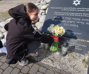  Złożenie kwiatów przez uczennicę przy tablicy upamiętniającą miejsce pochówku