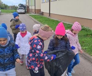 Dzieci zbierają śmieci wokół przedszkola.